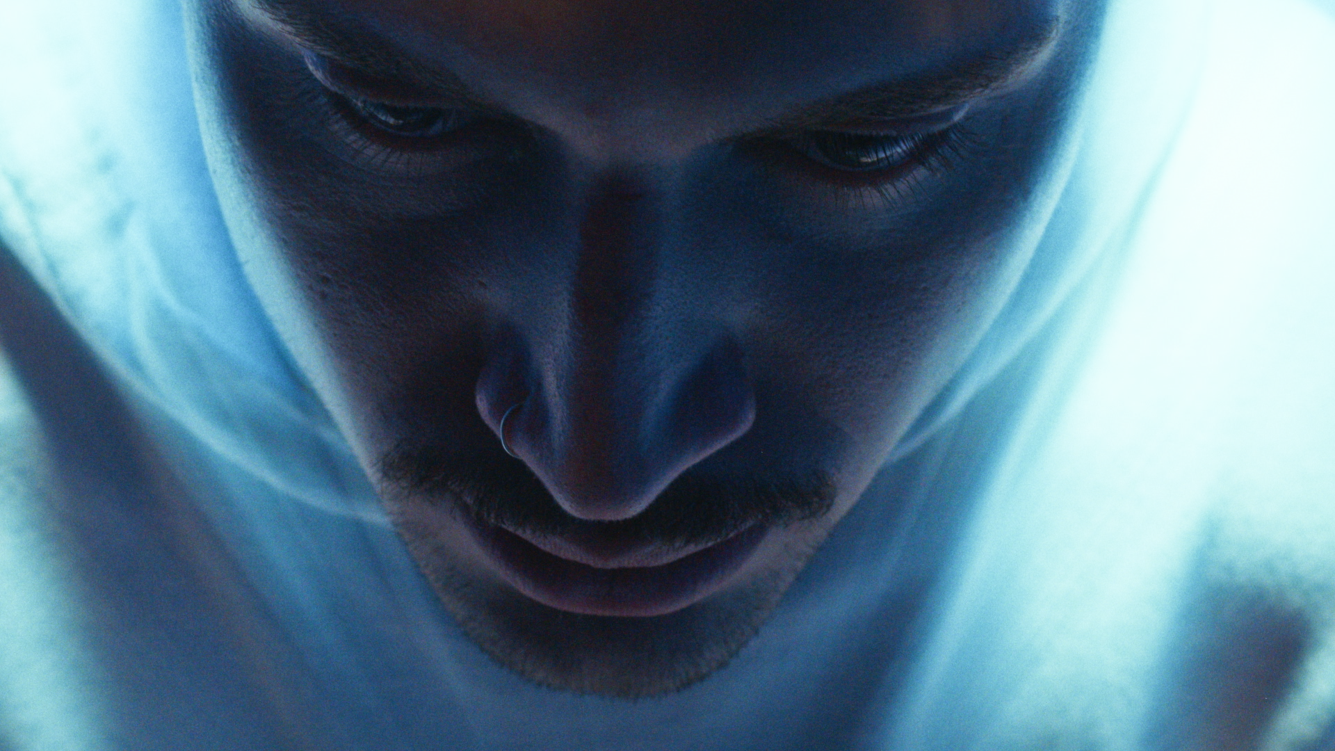 Blue-lit close-up of a face with eyes closed