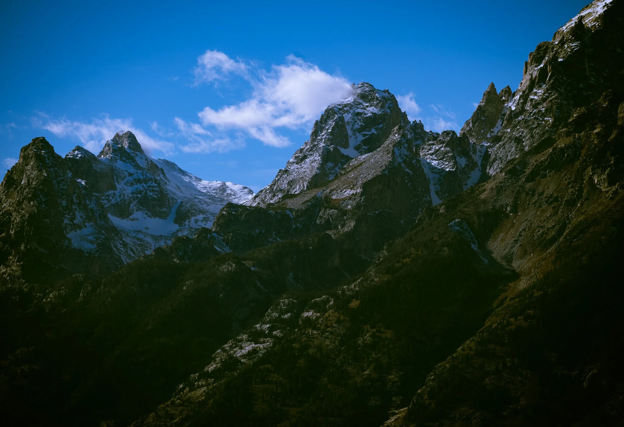 Snow-dusted Teton peaks beneath a blue sky