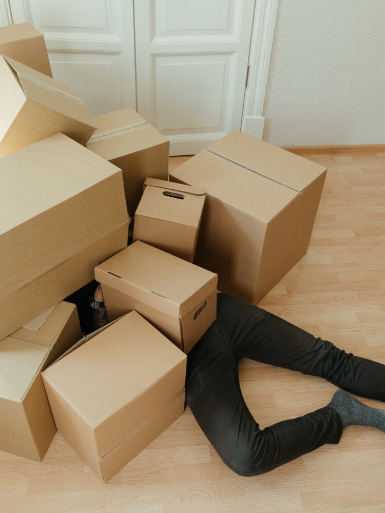 man under pile of boxes