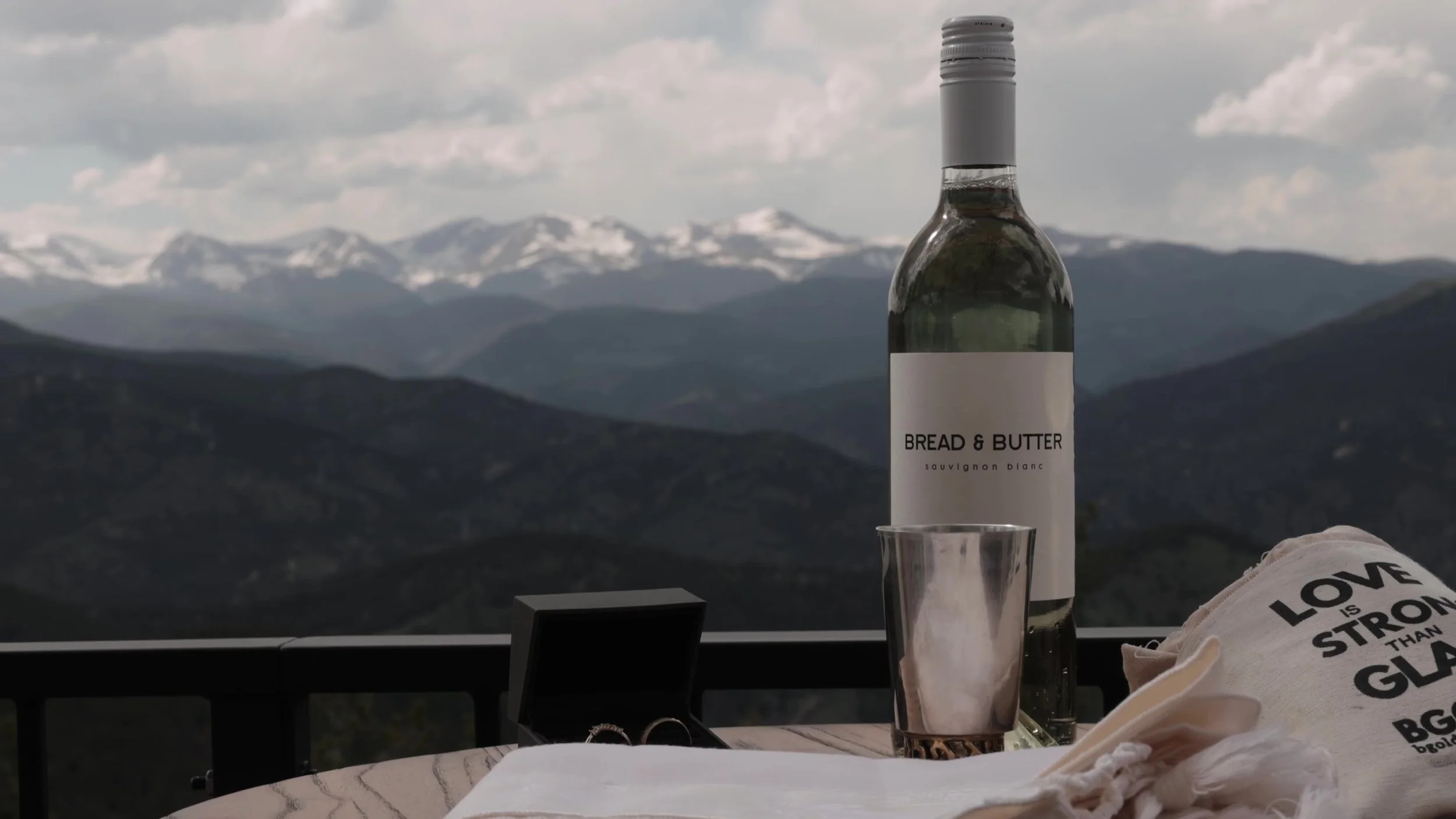 Wine bottle on a deck table at Northstar Gatherings with snow-capped Colorado mountains beyond Idaho Springs