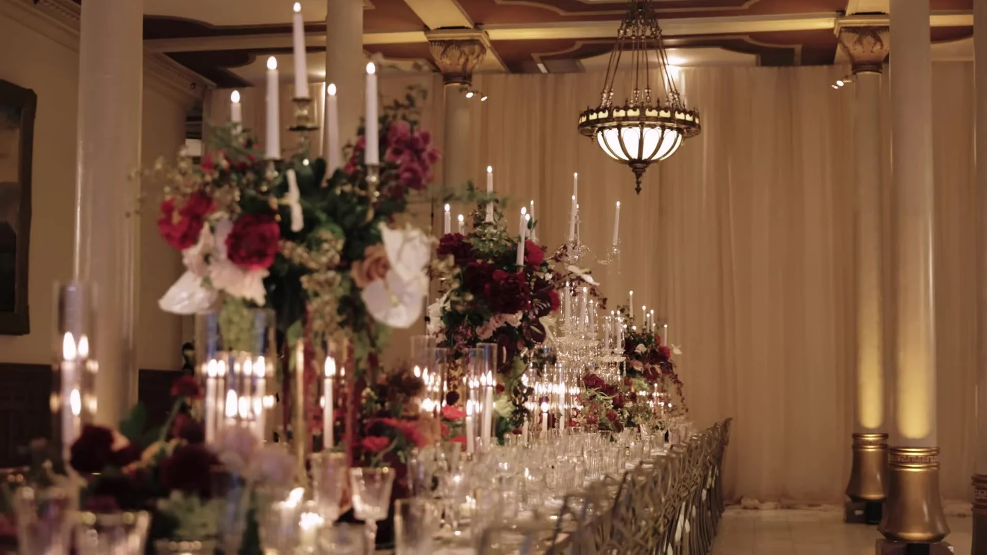 Long candlelit reception table with burgundy florals in a ballroom at The Driskill Hotel in Austin, Texas