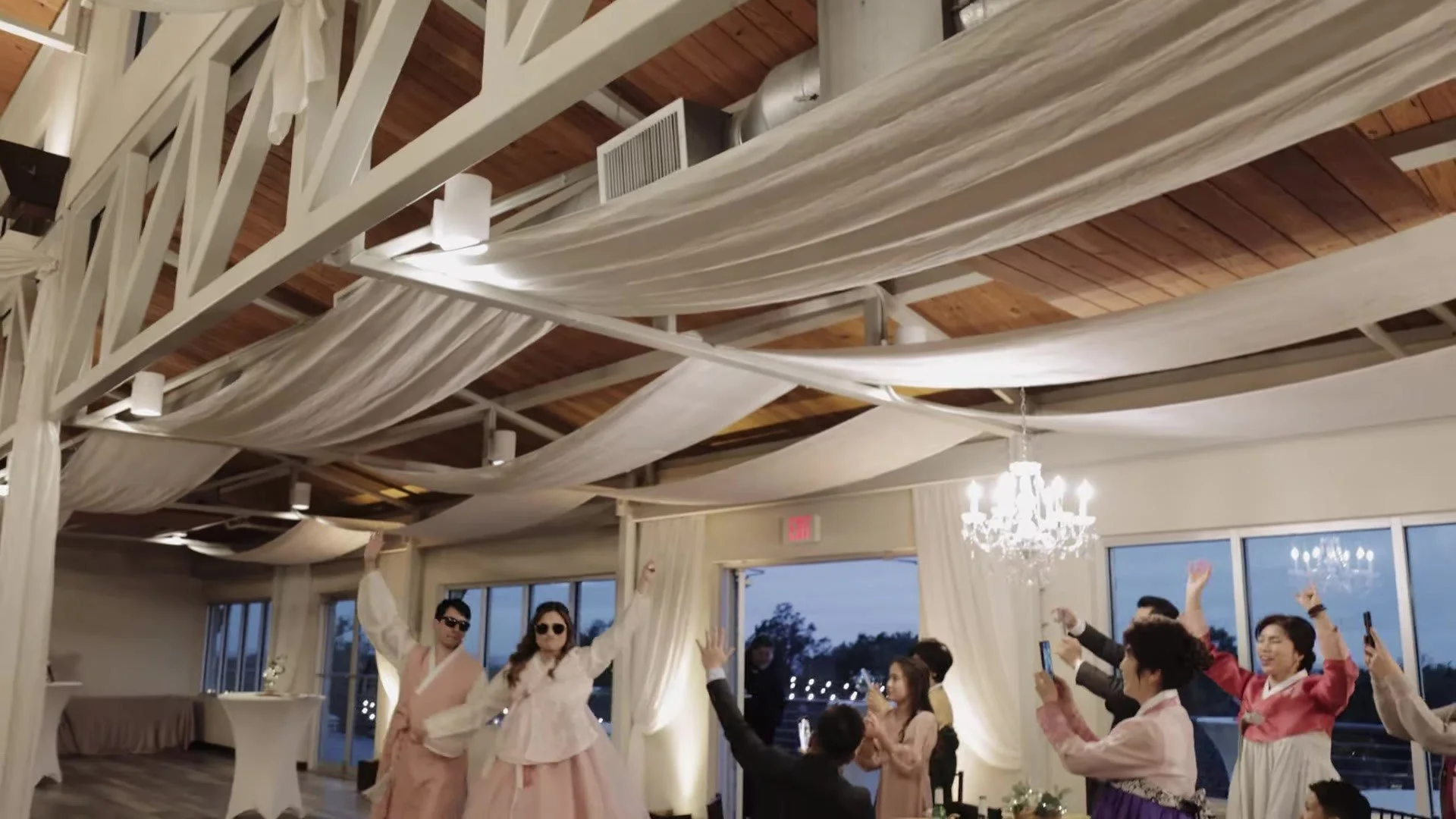 Manny and Jasmine in matching pink and white hanbok with sunglasses cheering at their Terrace Club Austin reception