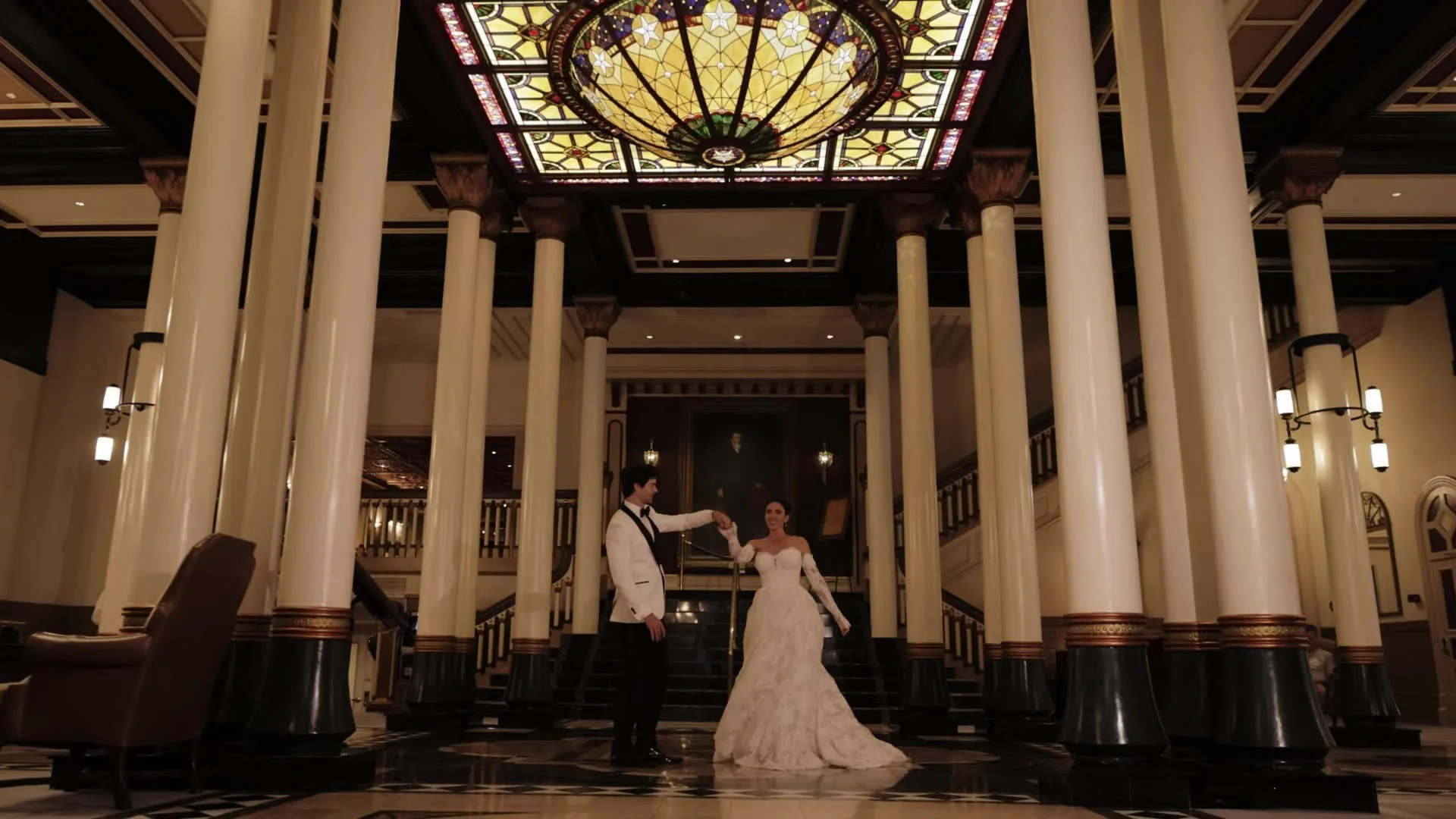 Grant and Anna dancing under the stained glass dome in the grand lobby of The Driskill Hotel in Austin, Texas