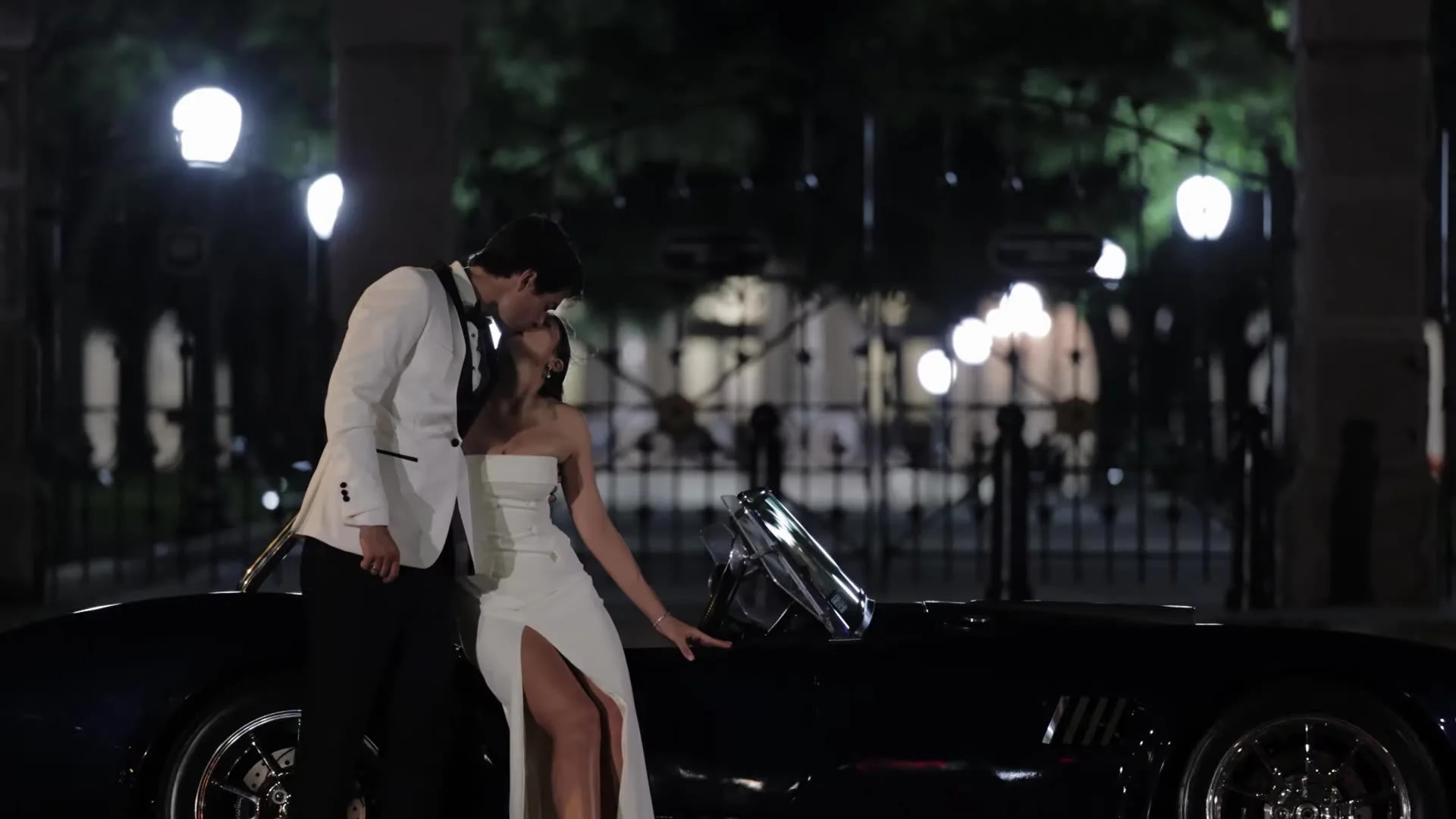 Grant and Anna kissing beside a classic convertible at night in Austin, Texas