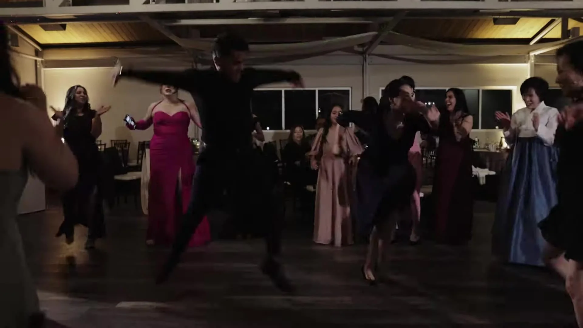 Guest leaping on the dance floor with a woman in blue and white hanbok at The Terrace Club reception