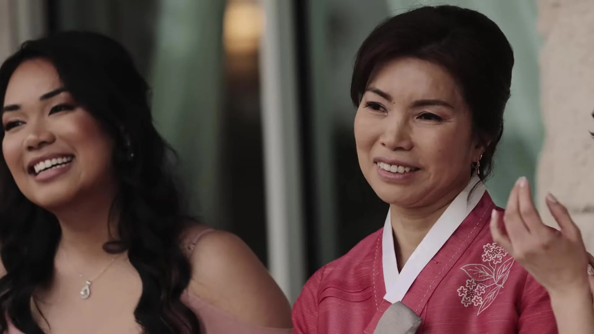 Wedding guest in a rose pink Korean hanbok smiling beside a younger woman at Manny and Jasmine's Austin wedding
