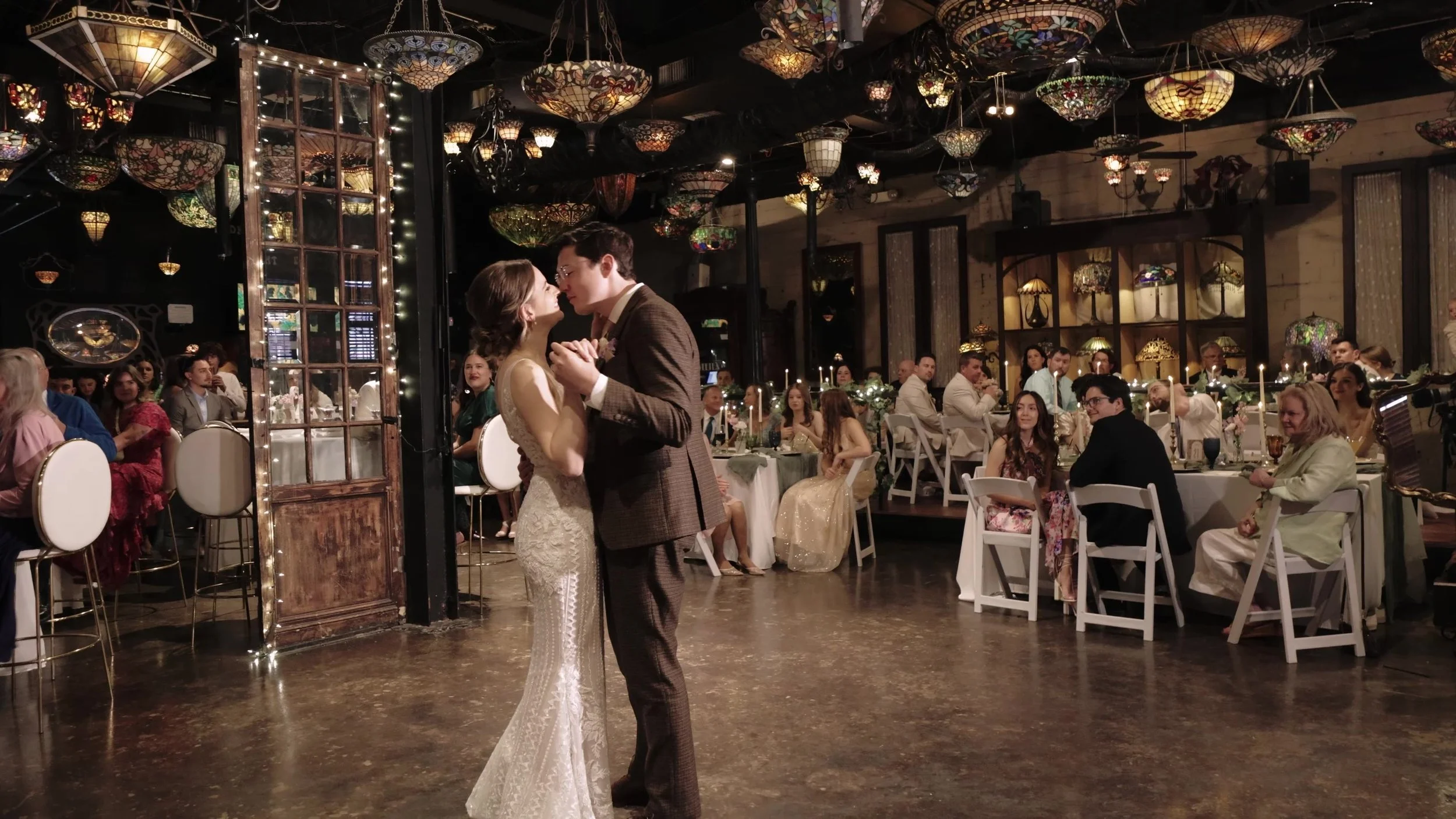Bride and groom first dance under Tiffany stained glass lamps at Nouveau Antique Art Venue in Houston, Texas