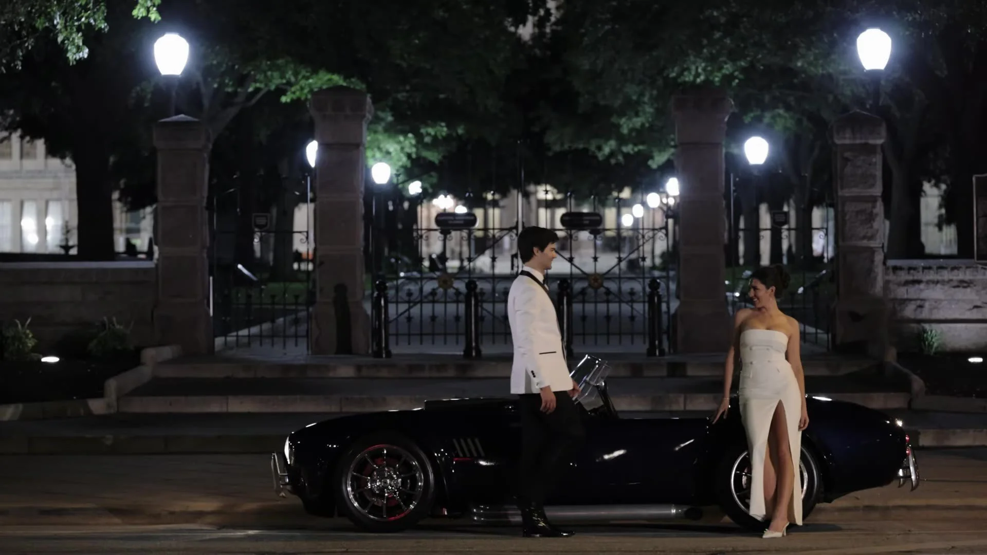 Grant and Anna with a classic Shelby Cobra convertible at night outside The Driskill in Austin, Texas