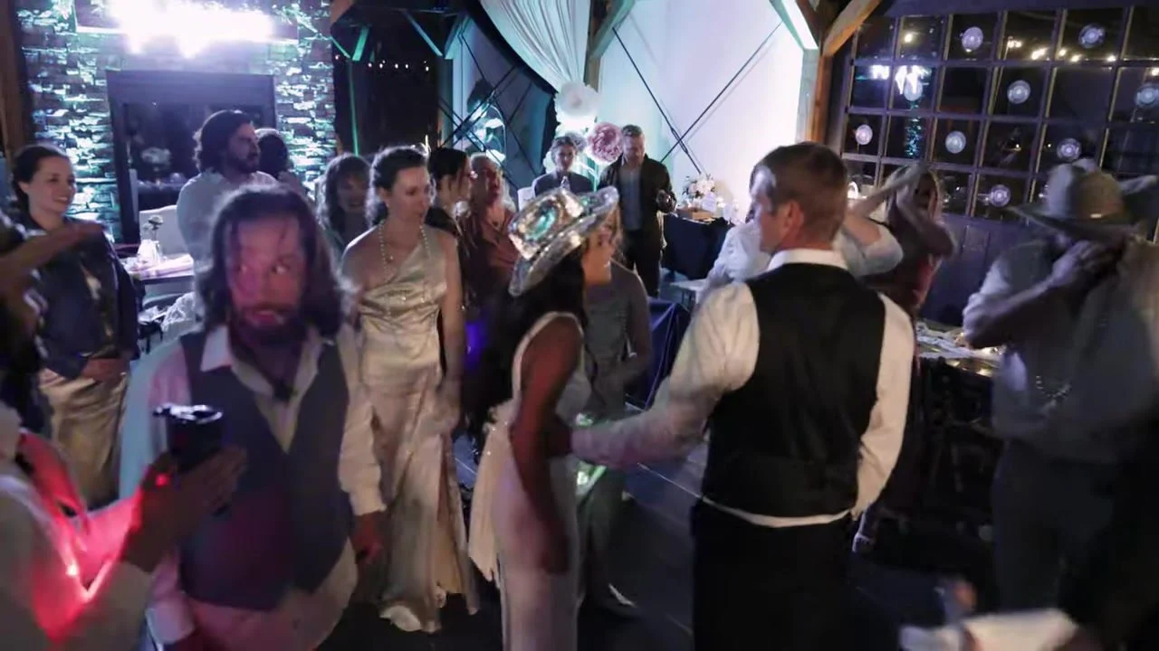 Sierra in a sequined cowboy hat dancing with Justin under blue party light at 3 Peaks Ranch