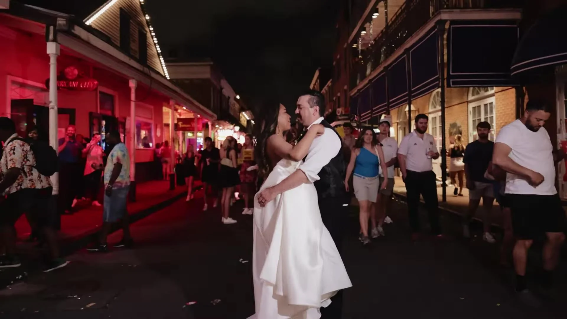 Blair and Gustavo embracing on a neon lit French Quarter street at night in New Orleans