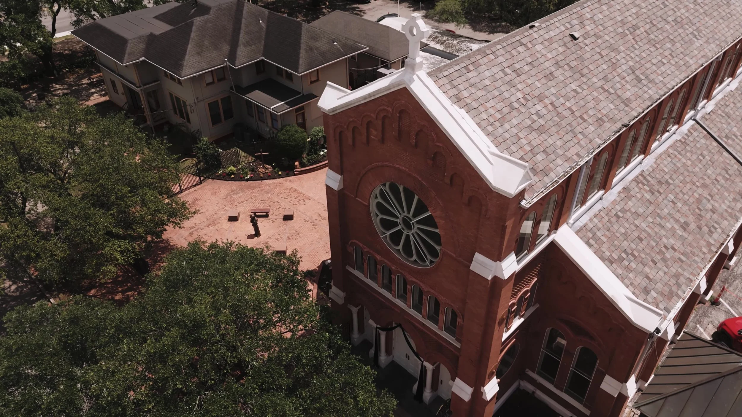 Aerial view of a red brick church with rose window and courtyard near Nouveau Antique Art Venue wedding weekend in Houston, Texas