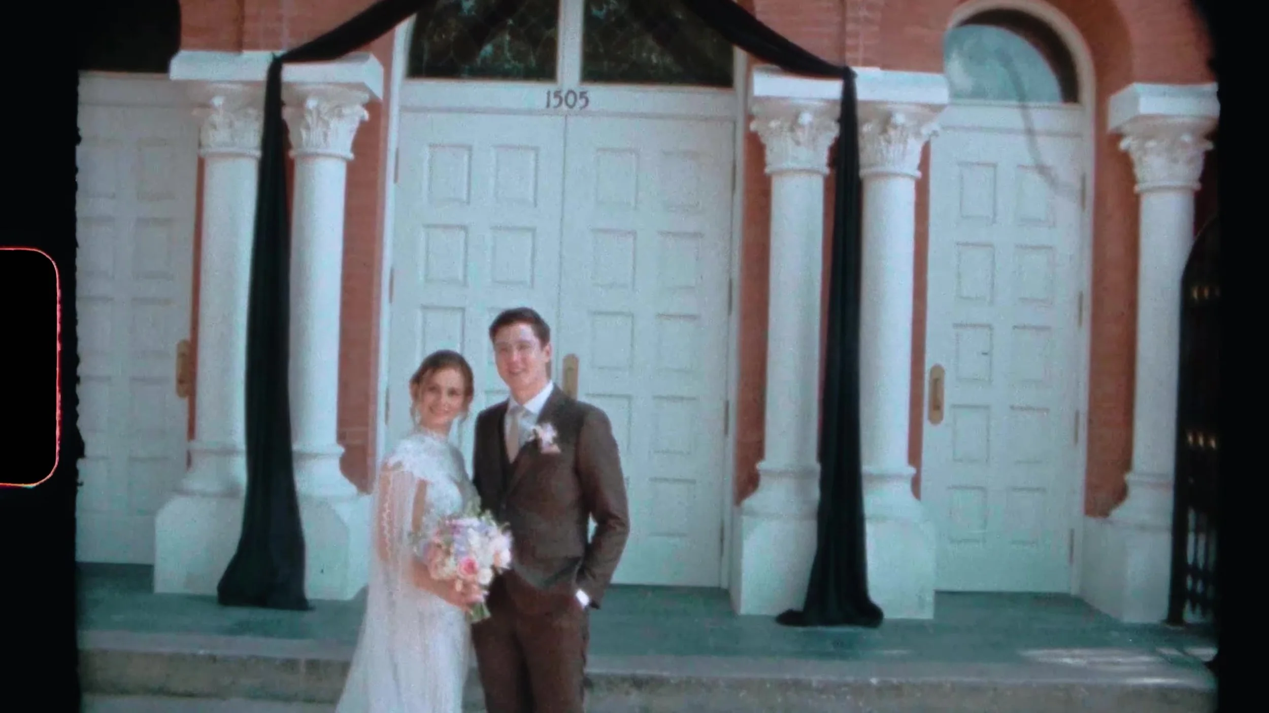 Bride and groom standing at white doors marked 1505 outside a red brick Houston wedding venue on film