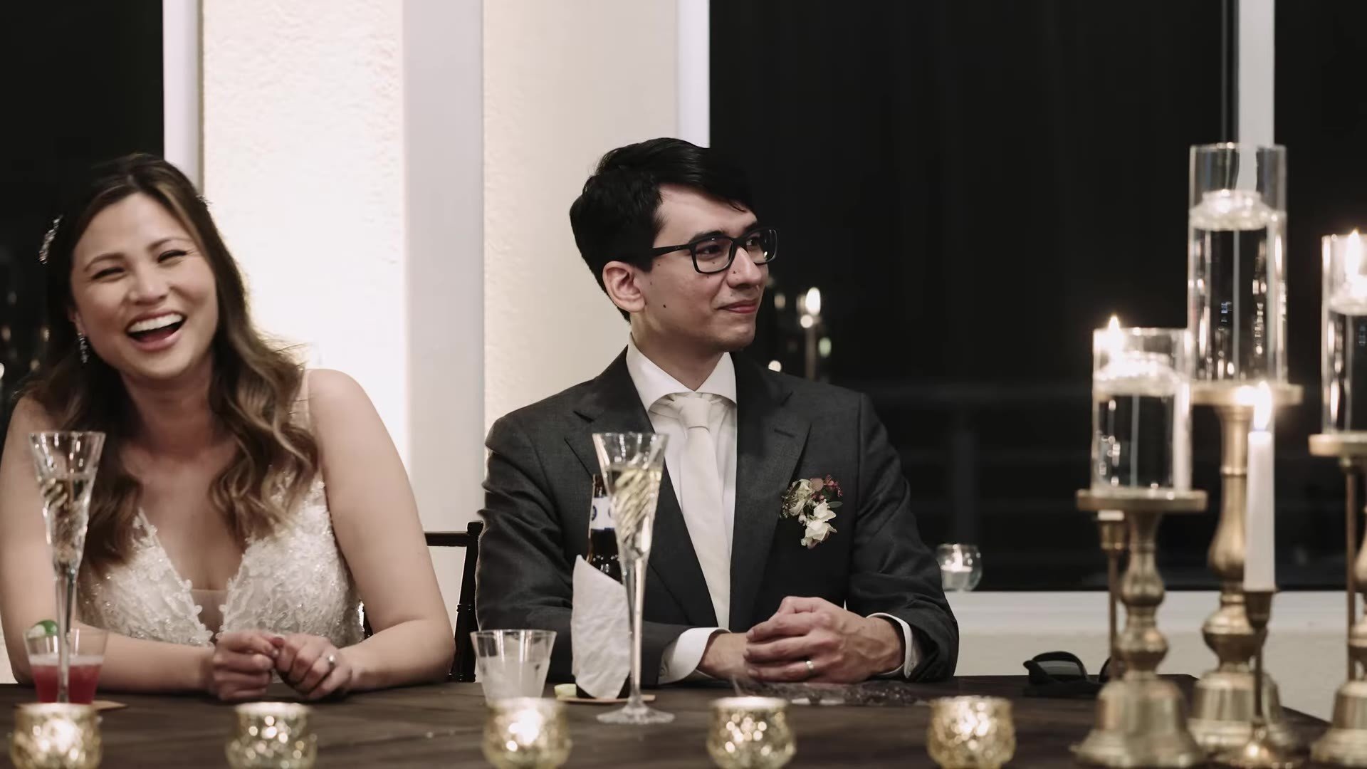 Manny and Jasmine laughing at their sweetheart table with gold candle holders at The Terrace Club reception