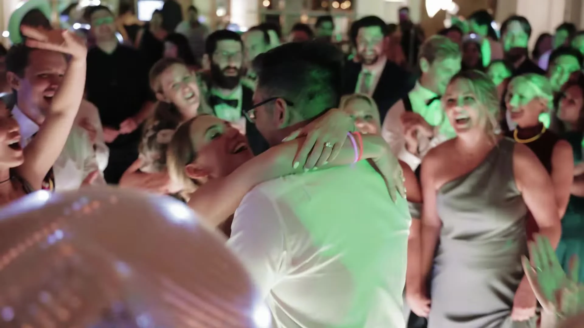 Jason and Rachel hugging on a packed dance floor at Canyonwood Ridge under green party lights in Texas