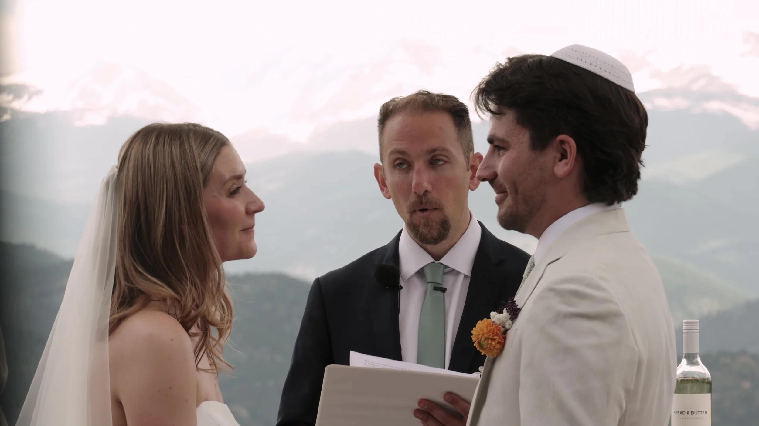 Bride, groom, and officiant at the outdoor ceremony at Northstar Gatherings in Idaho Springs, Colorado, with the mountain range behind them