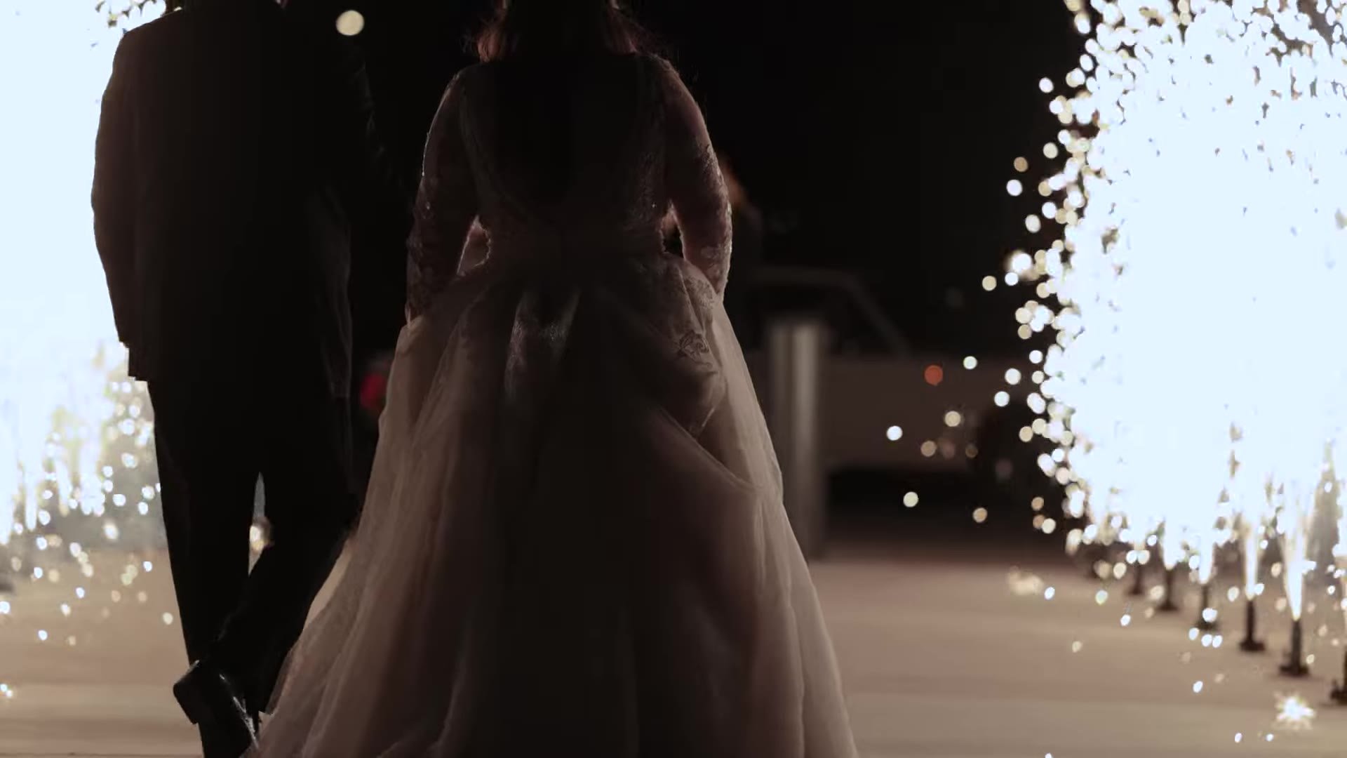 Gabby and Nic walking through cold sparkler fountains at night after their Q2 Stadium wedding in Austin