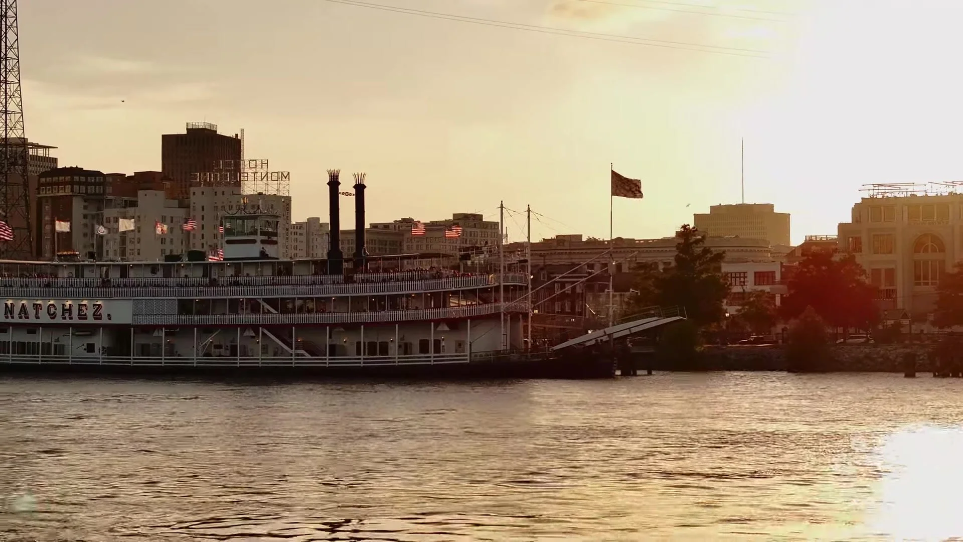 Steamboat Natchez docked on the Mississippi with Hotel Monteleone and New Orleans skyline at sunset