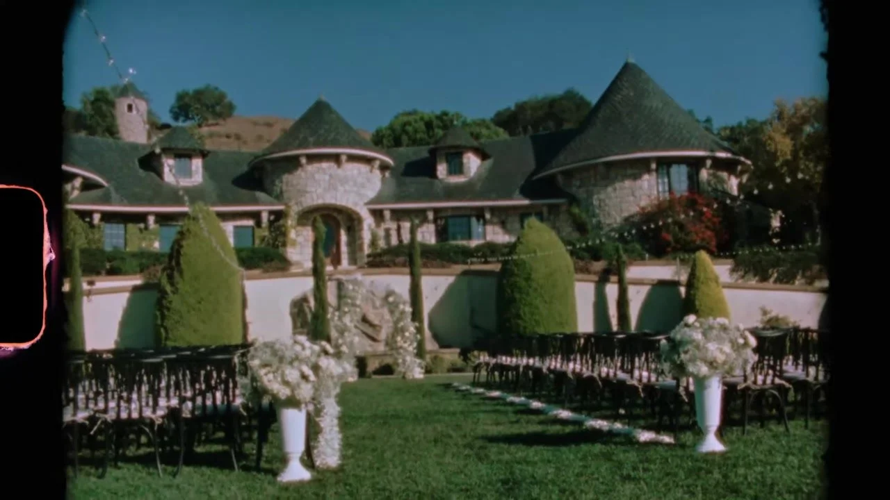 Super 8 view of the ceremony lawn, black chairs, white florals, and the stone chateau with turrets