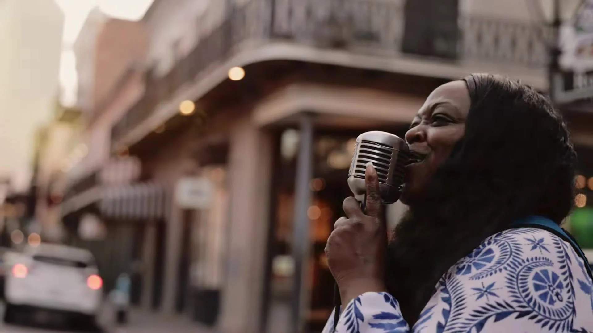 Jazz singer with vintage microphone on a French Quarter street under wrought iron balconies in New Orleans
