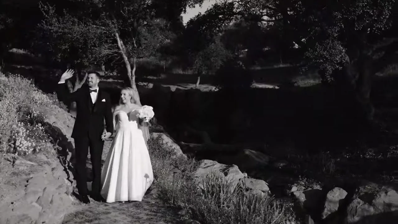 Black and white still of Alex and Santi walking a stone path
