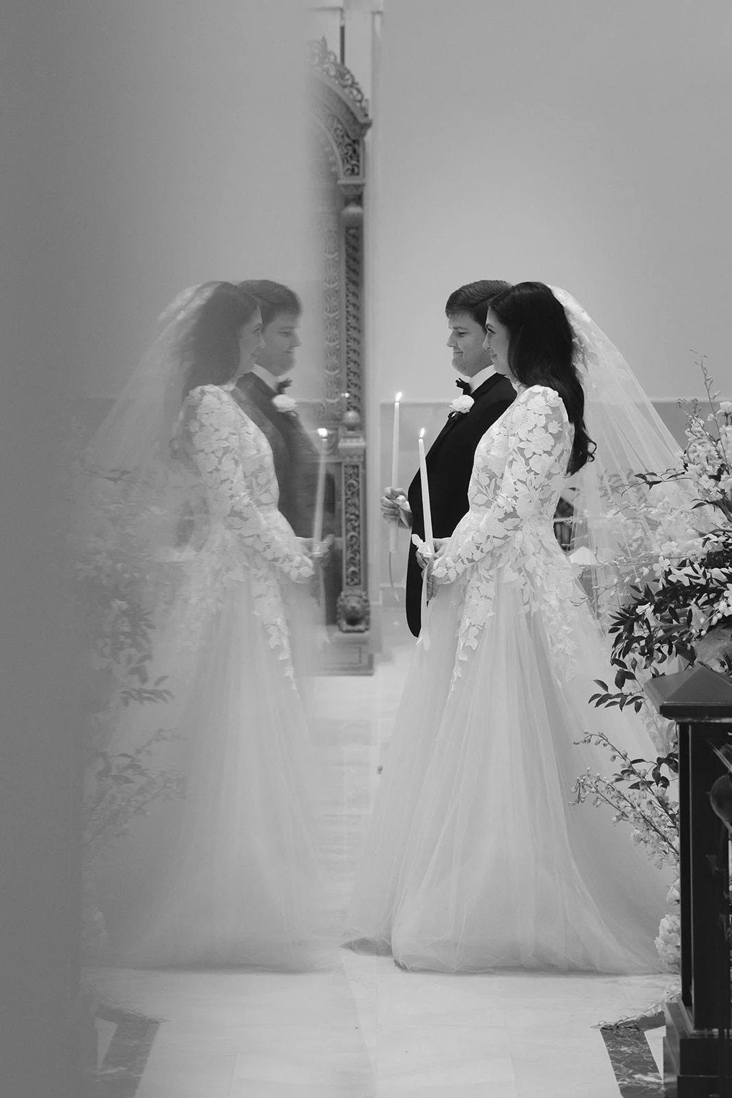 Black and white photo of bride and groom lighting a unity candle reflected in a mirror