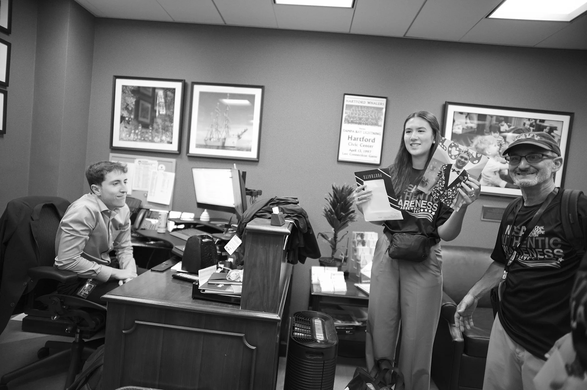 Cristina holds up a portrait of Zack for the office staff.