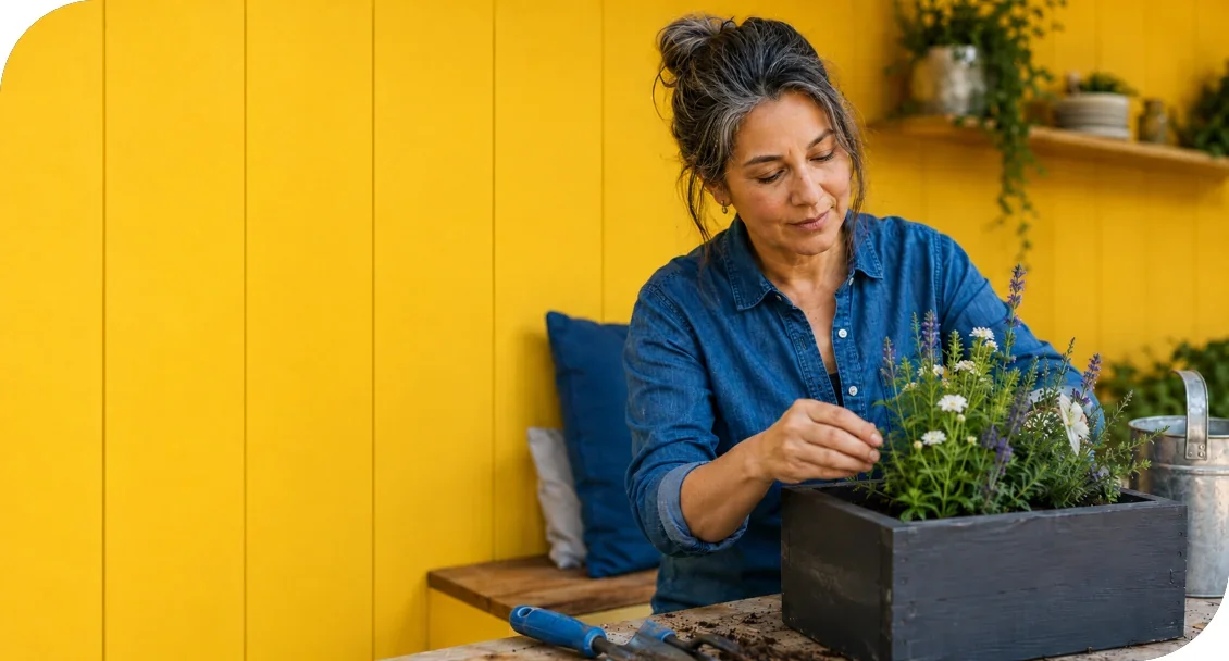 A woman tending flowering plants in a planter box.