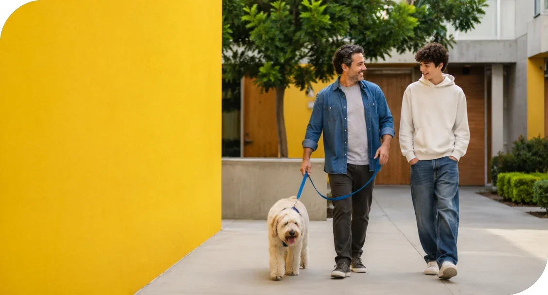 Two people walking outdoors together with a dog.