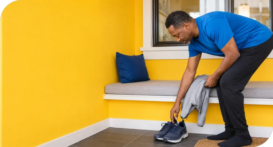 A man reaching for athletic shoes beside a bench.