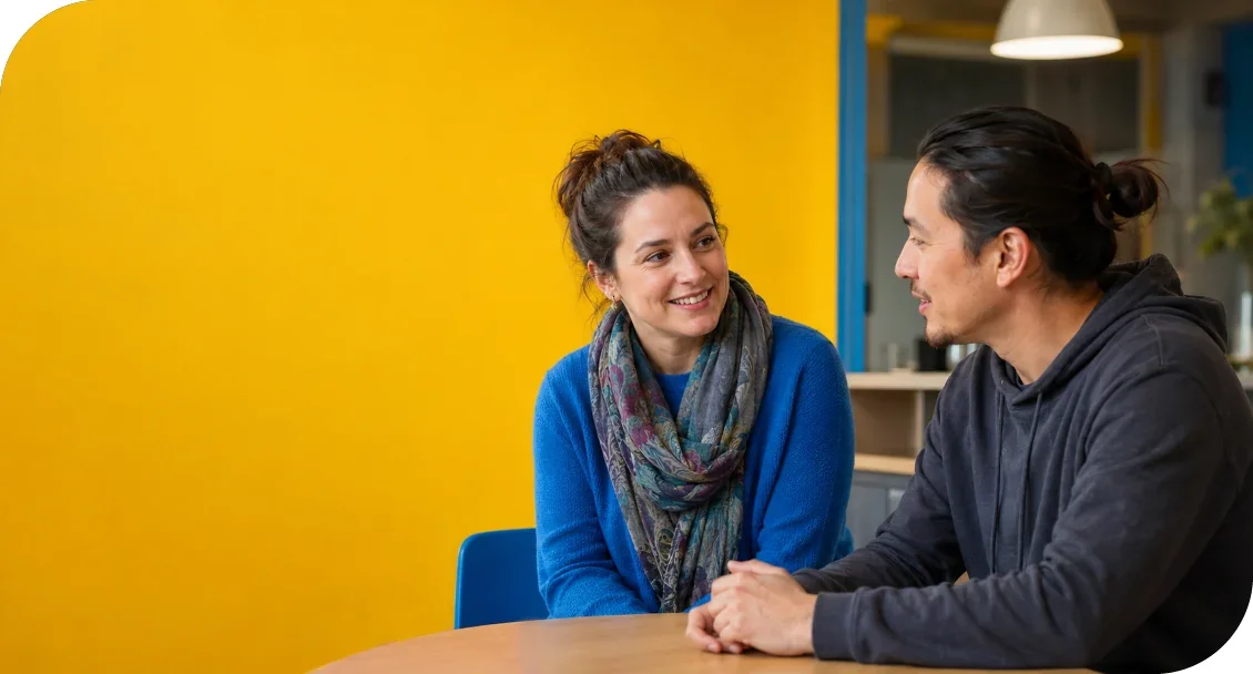 A woman and man seated at a table, smiling and talking together.
