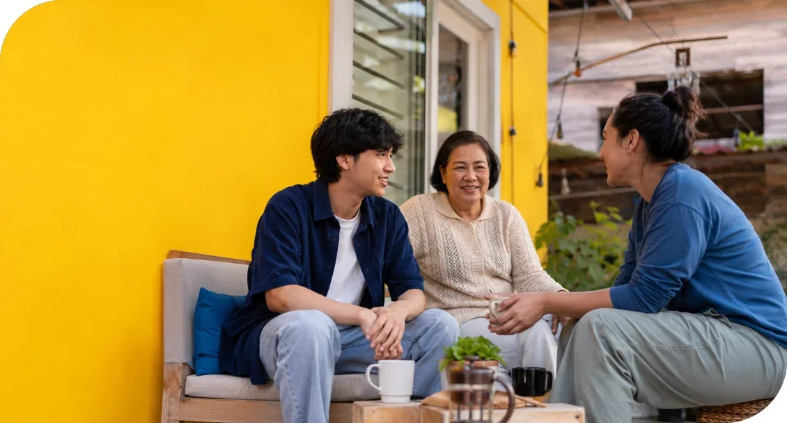Three people sitting together and talking around a small table.