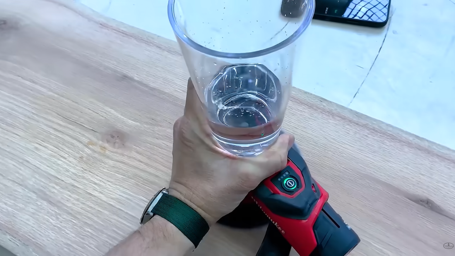 Glass of water sitting on the running Milwaukee M12 6-inch sander showing how little it vibrates