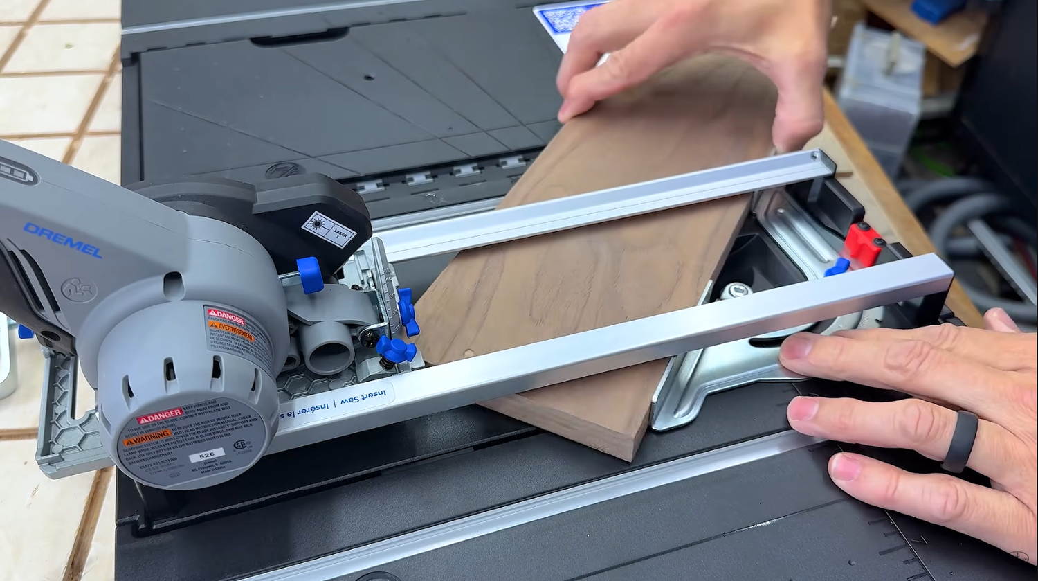 Dremel Blueprint 12V saw riding in the saw kit guide rail with the built-in miter gauge set for a cut