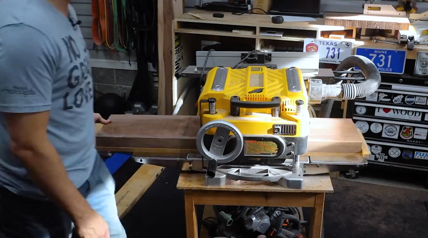 DeWALT DW735X thickness planer on a workbench with a rough board feeding through the infeed table