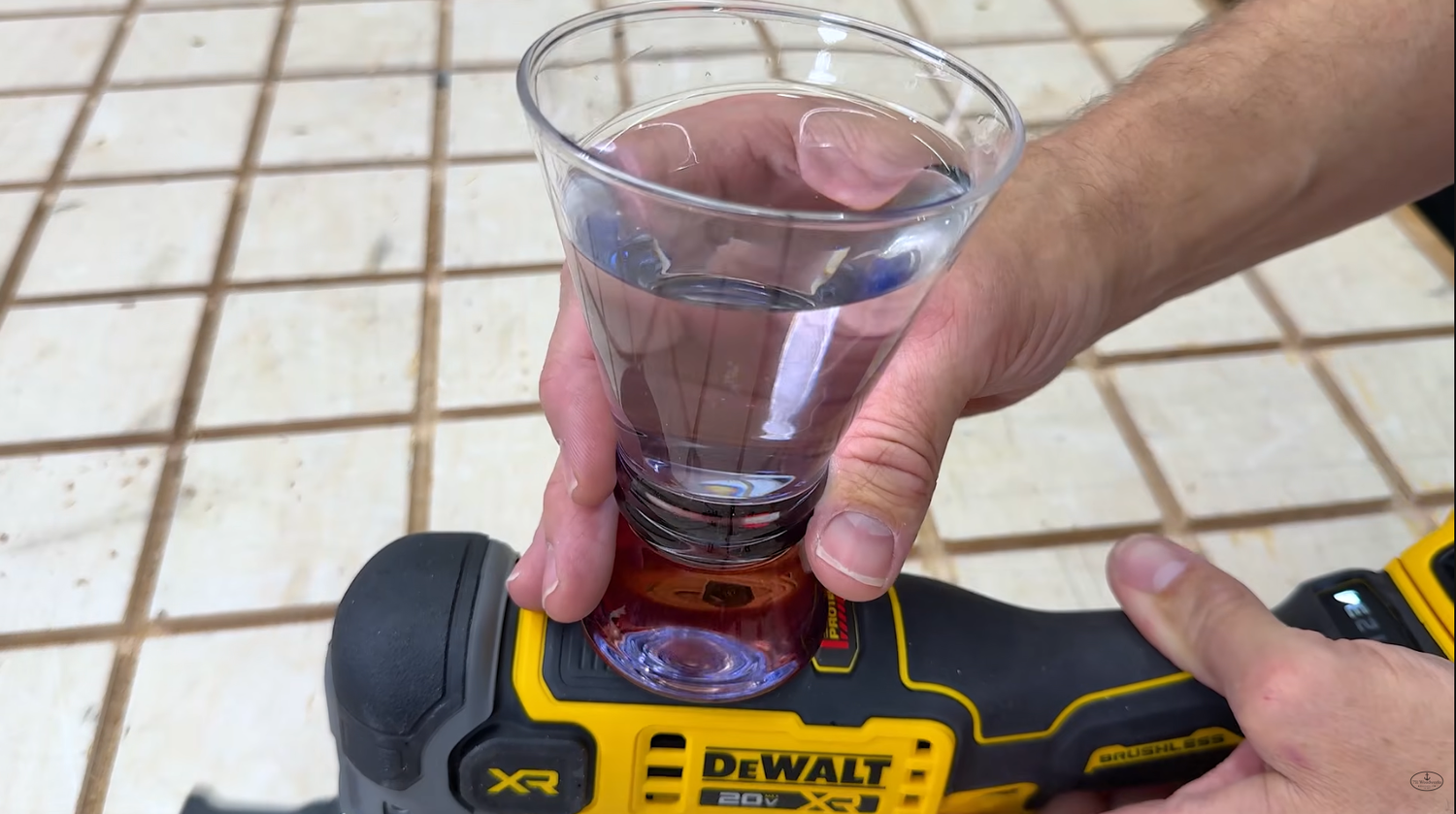 Cup of water sitting on a running DeWALT DCS359B oscillating multi-tool with almost no ripples