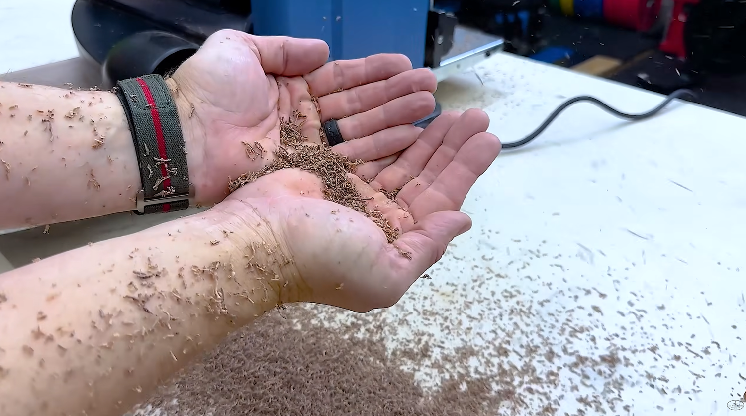 Fine wood shavings from a helical head thickness planer piled beside a planed board