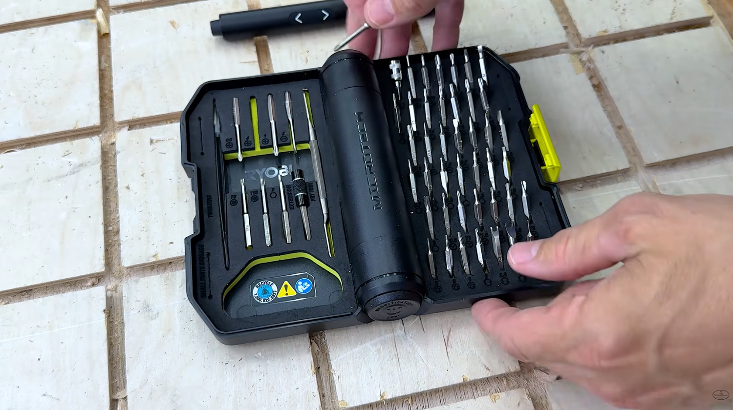 RYOBI Microtechnology screwdriver kit FVD02K open on a workbench showing micro bits, pry bar, tweezers and the electric screwdriver
