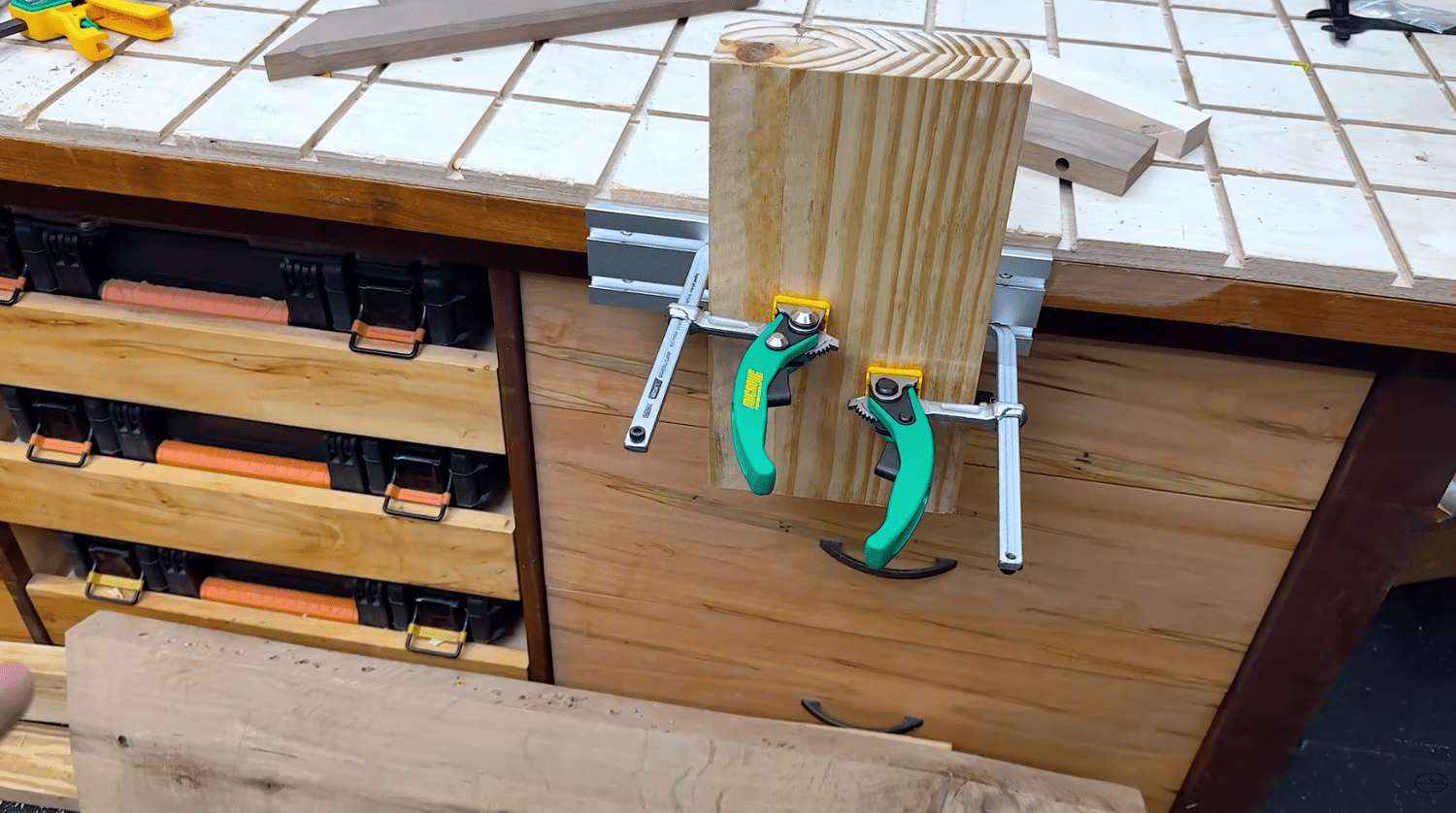 MicroJig ratchet clamps holding a workpiece vertically in the BenchMount router table track on a workbench