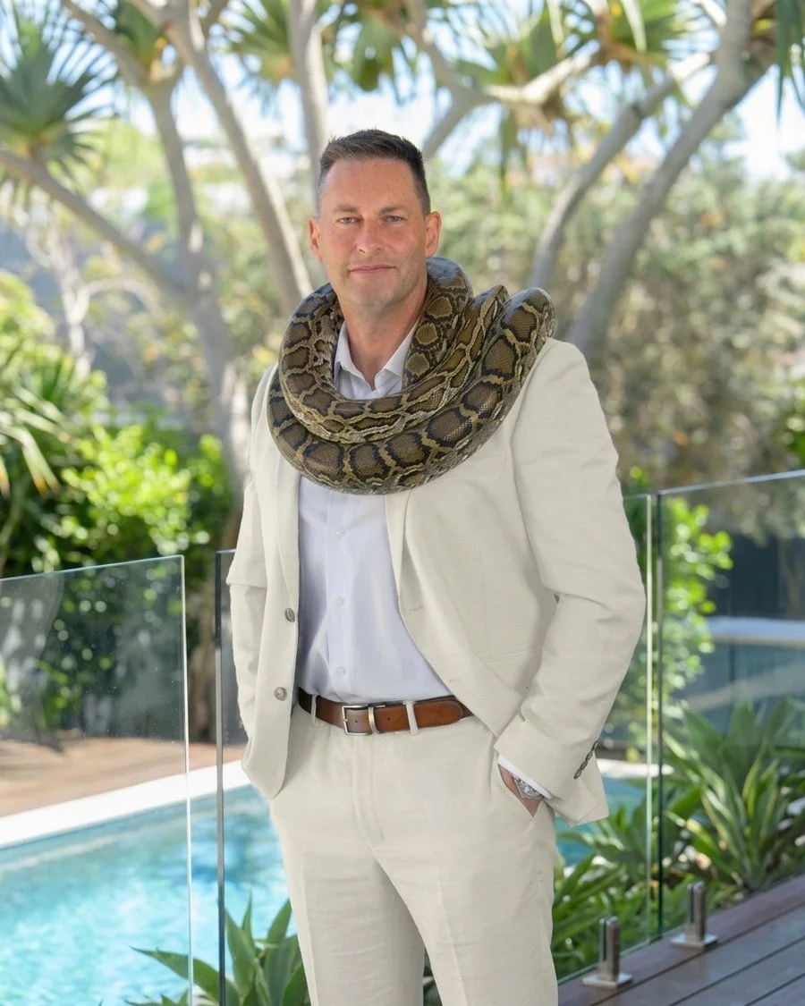 Jason Robertson, business strategist and mind and body transformation coach, in an AI-generated white suit with a python around his neck
