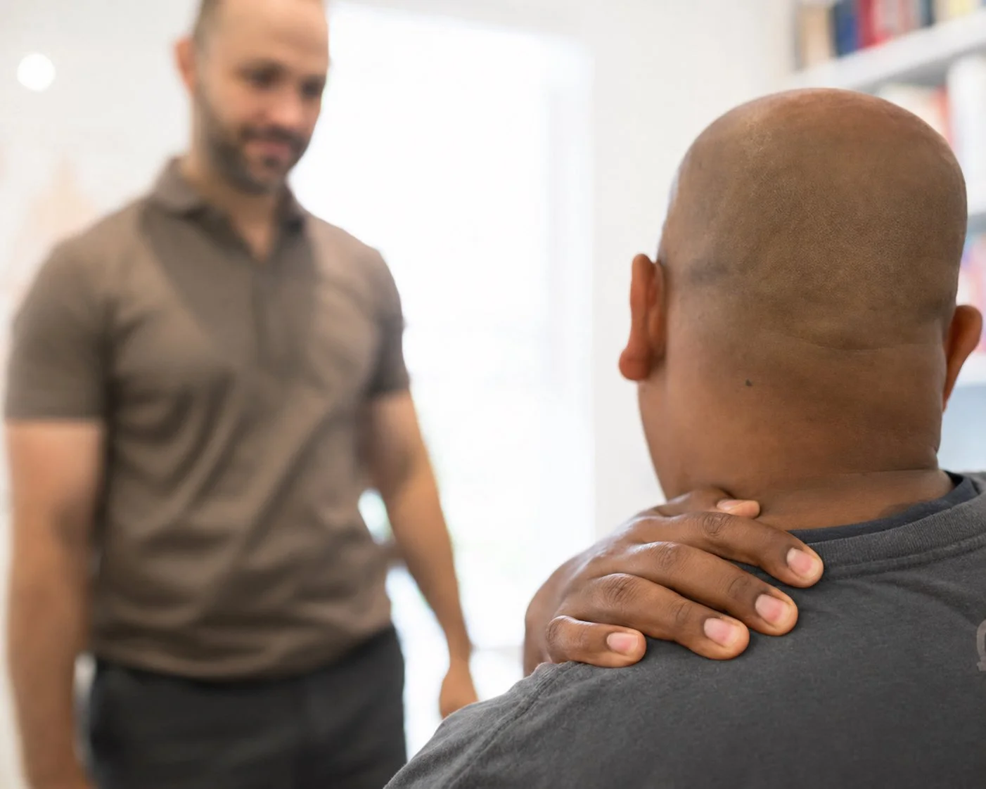 A person holding their neck during a consultation at ONE80 Health in Toronto