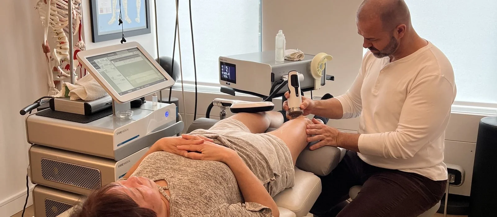 Dr. Nick Tsaggarelis delivering shockwave therapy to a patient's knee at ONE80 Health in Toronto
