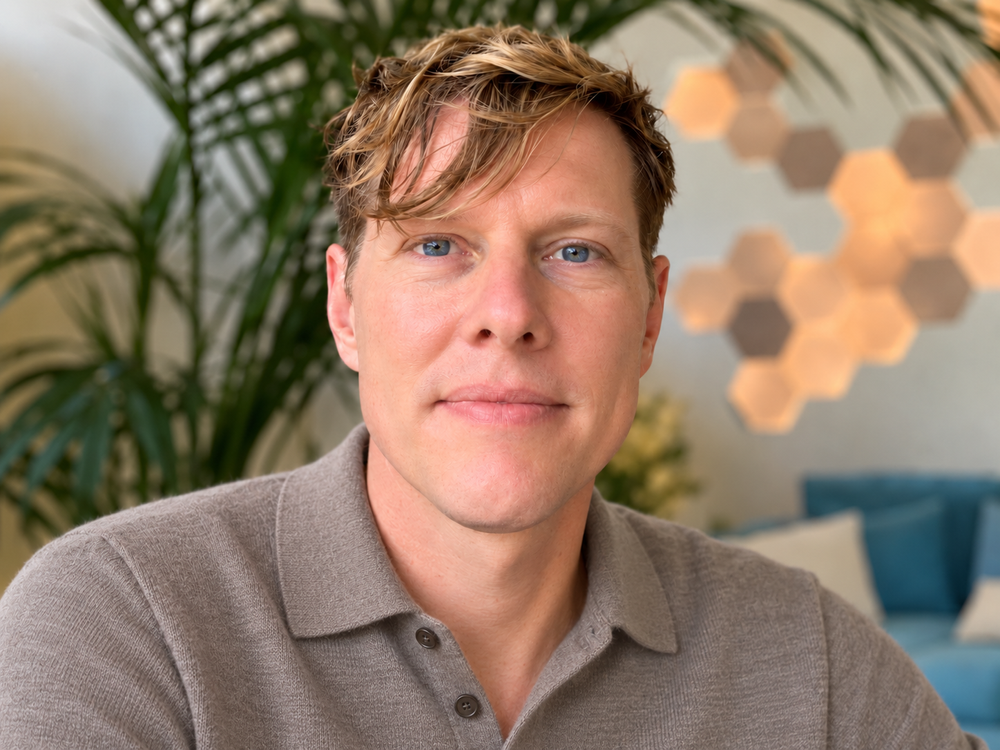 Jamie Fortin, LMFT, wearing a taupe shirt, with plants in the background.