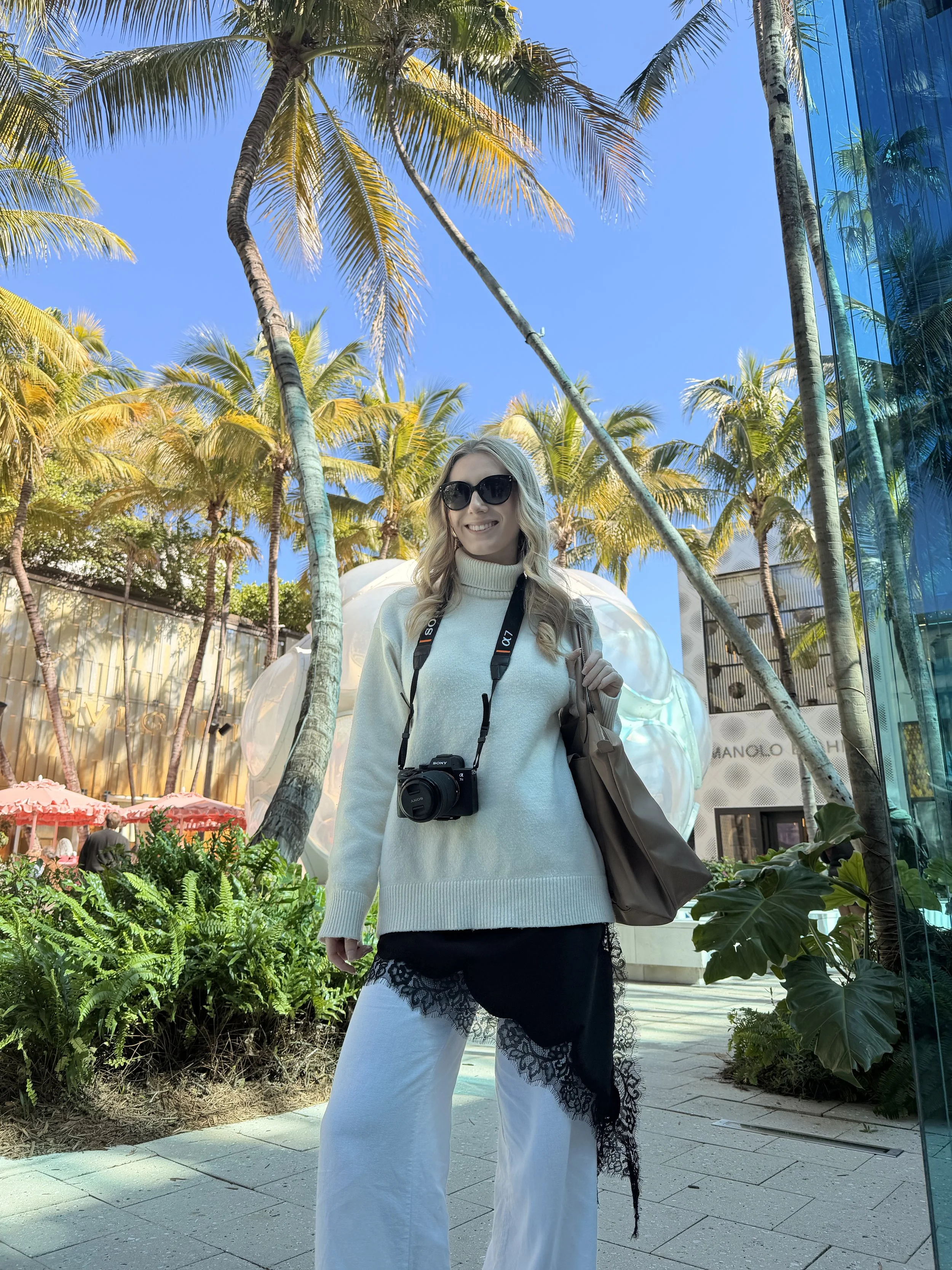 Woman with a camera beneath palm trees in Miami