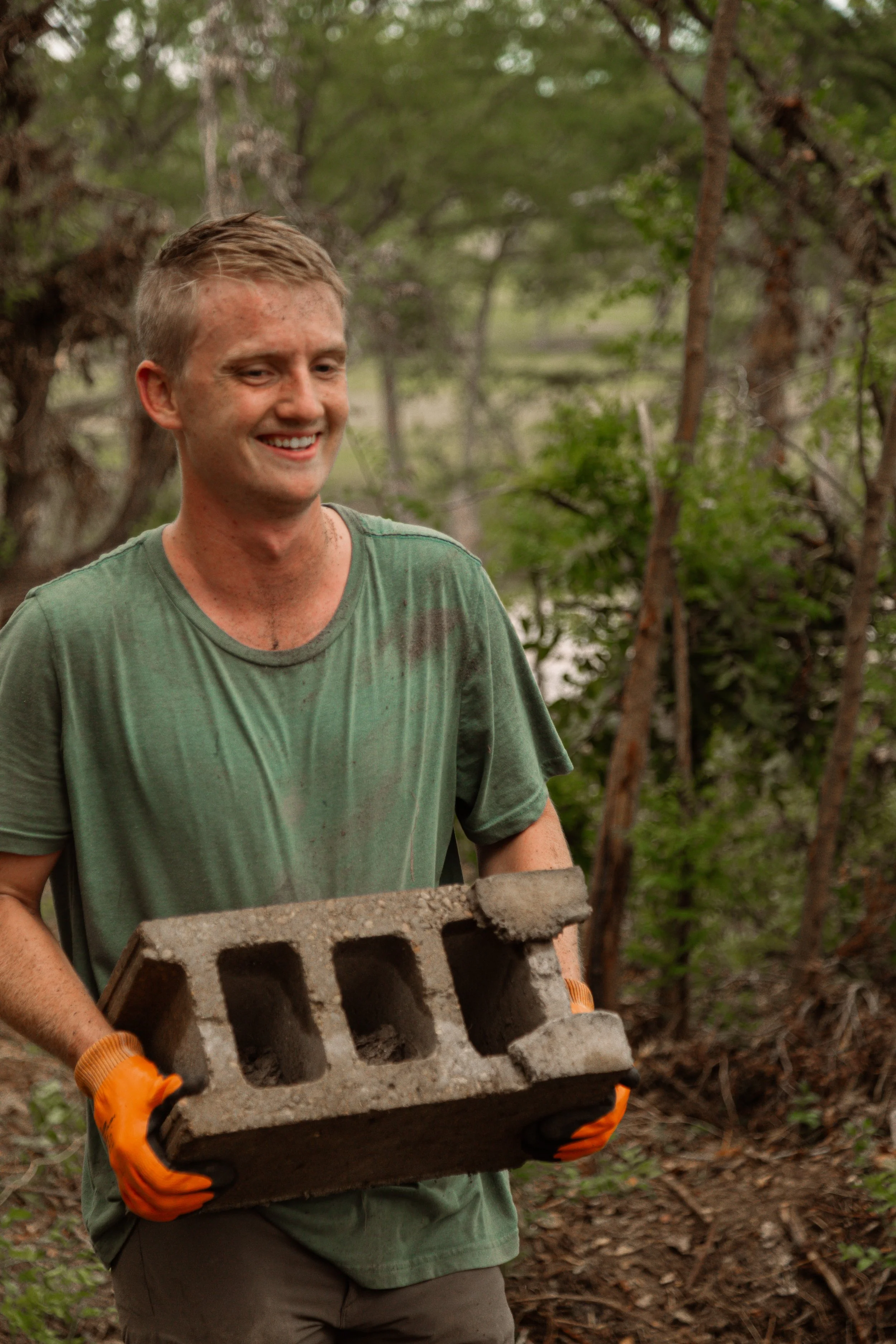 Volunteer carrying cinder block with a smile