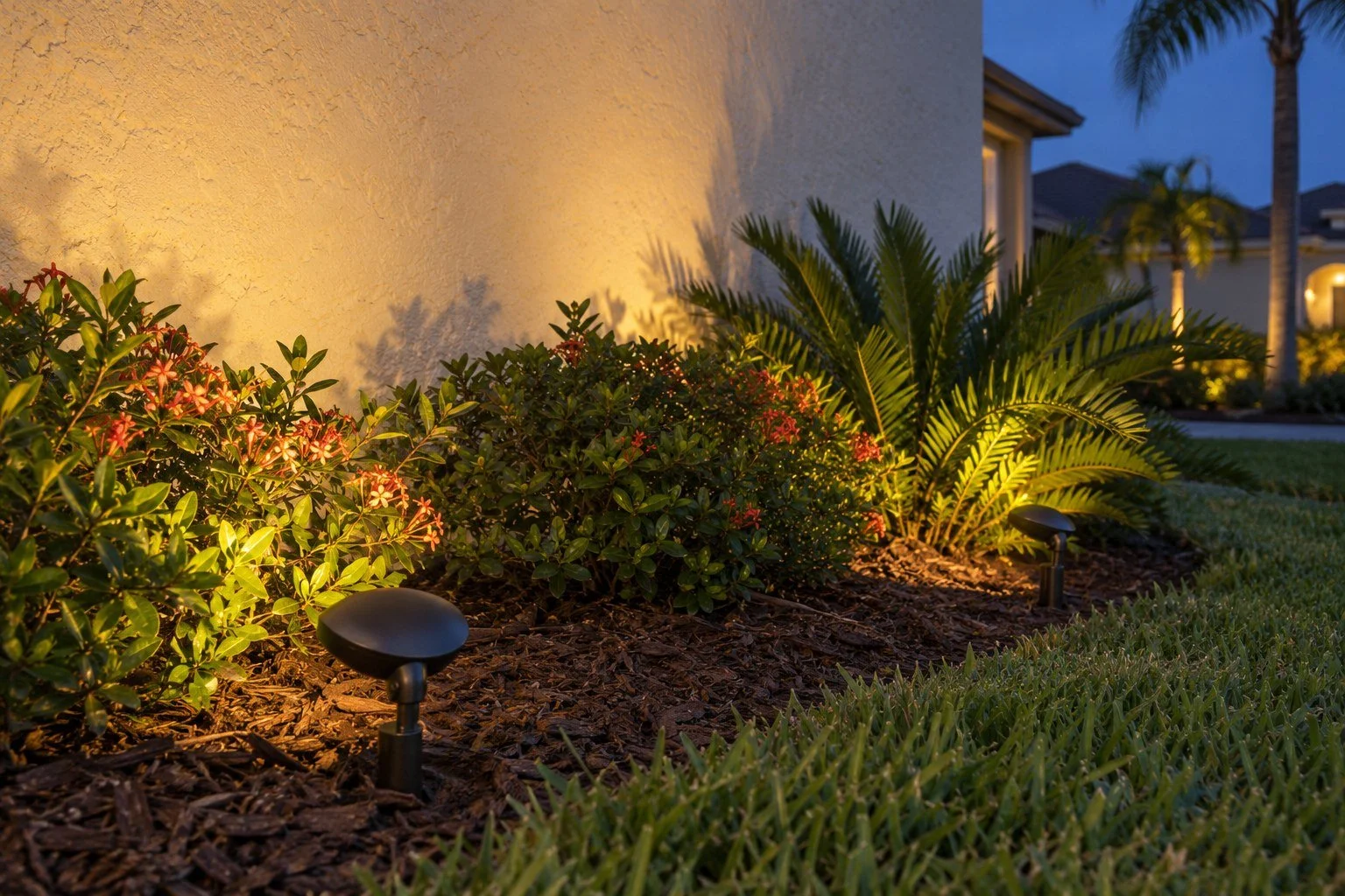 AI-generated Tampa Bay landscape lighting concept: Broad flood lights wash a stucco wall and foundation planting with warm light.