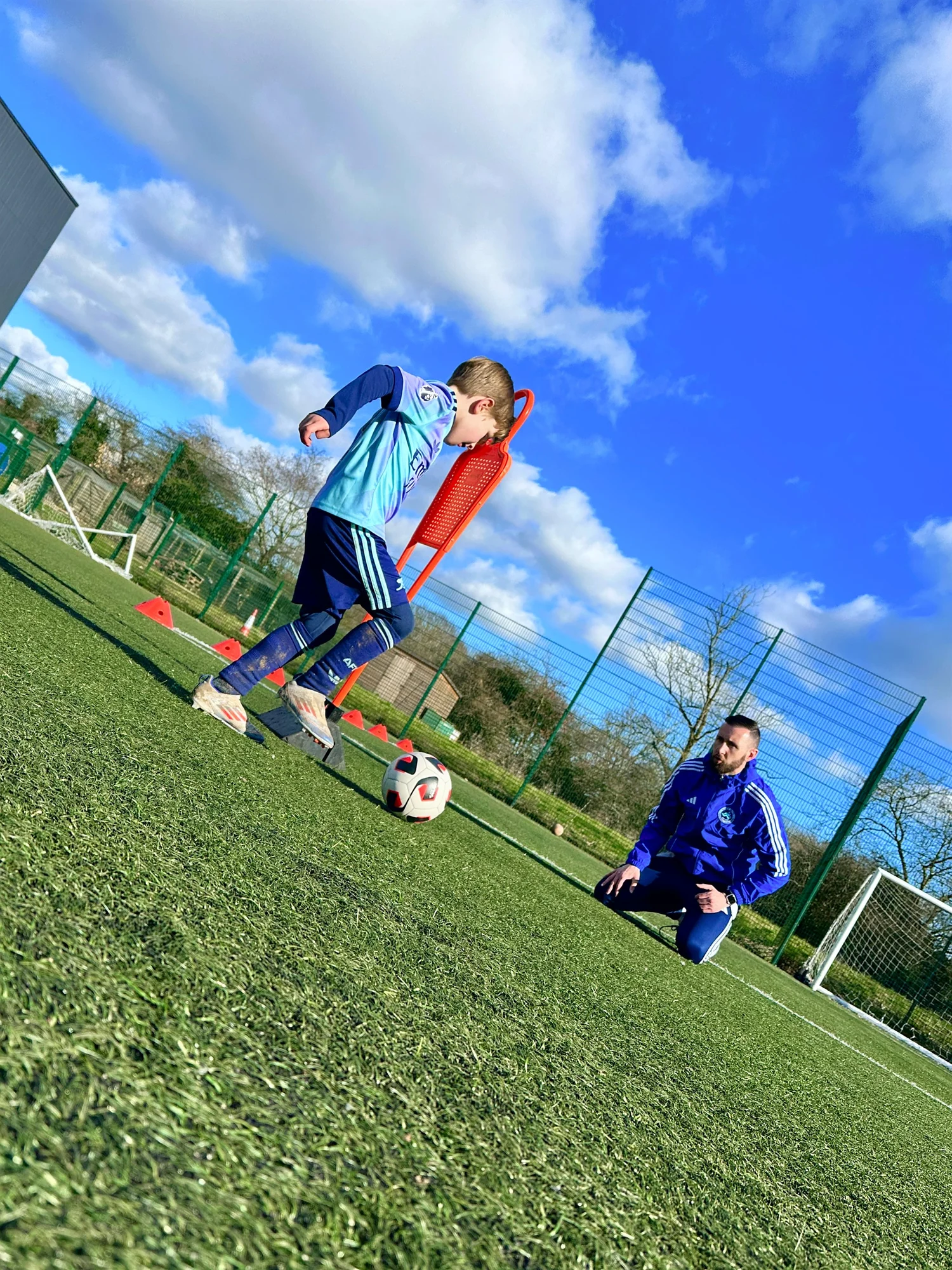 EEFC coach guiding a young footballer through a training drill