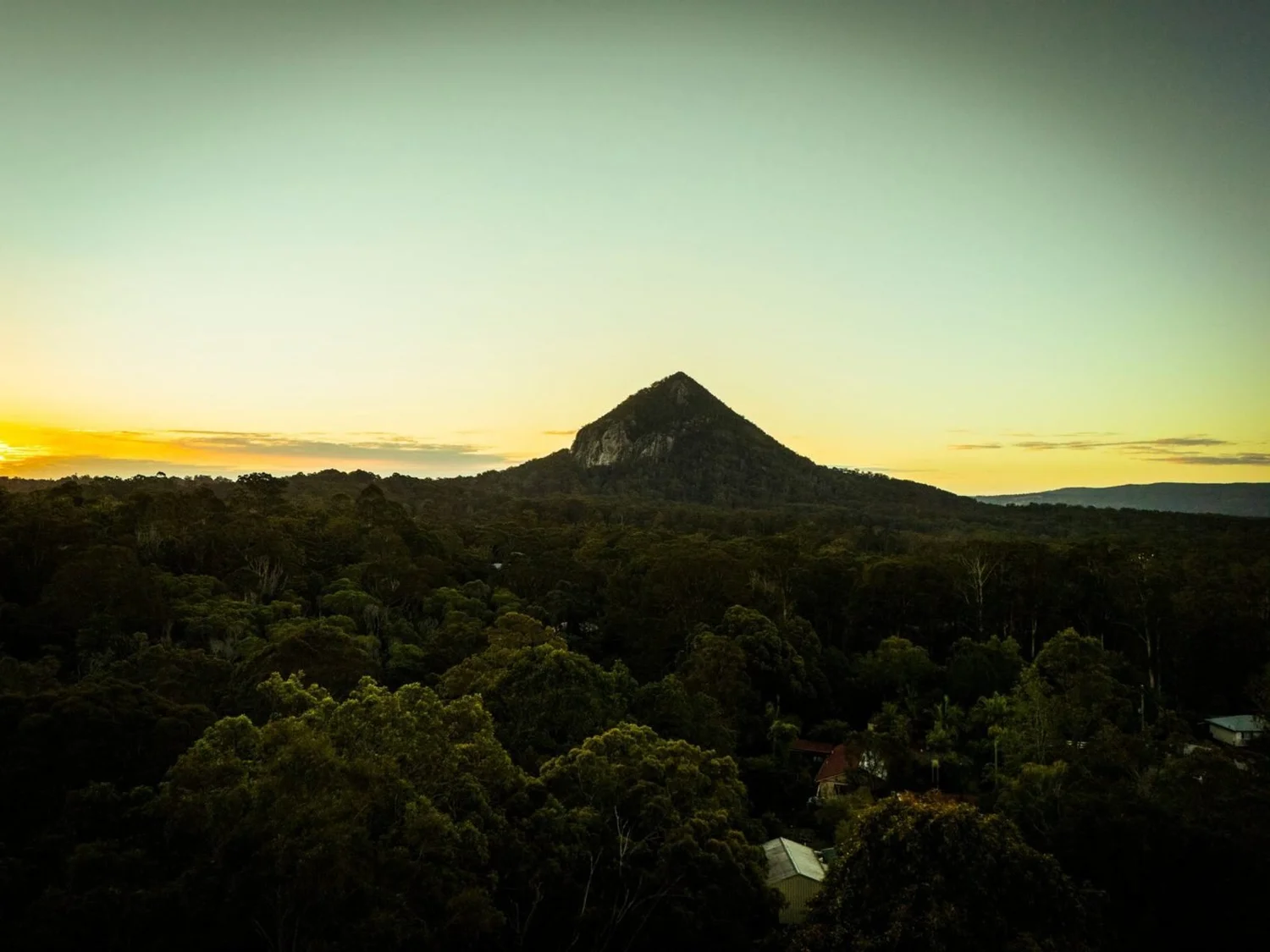 Drone photo of a hinterland mountain at sunrise above forest