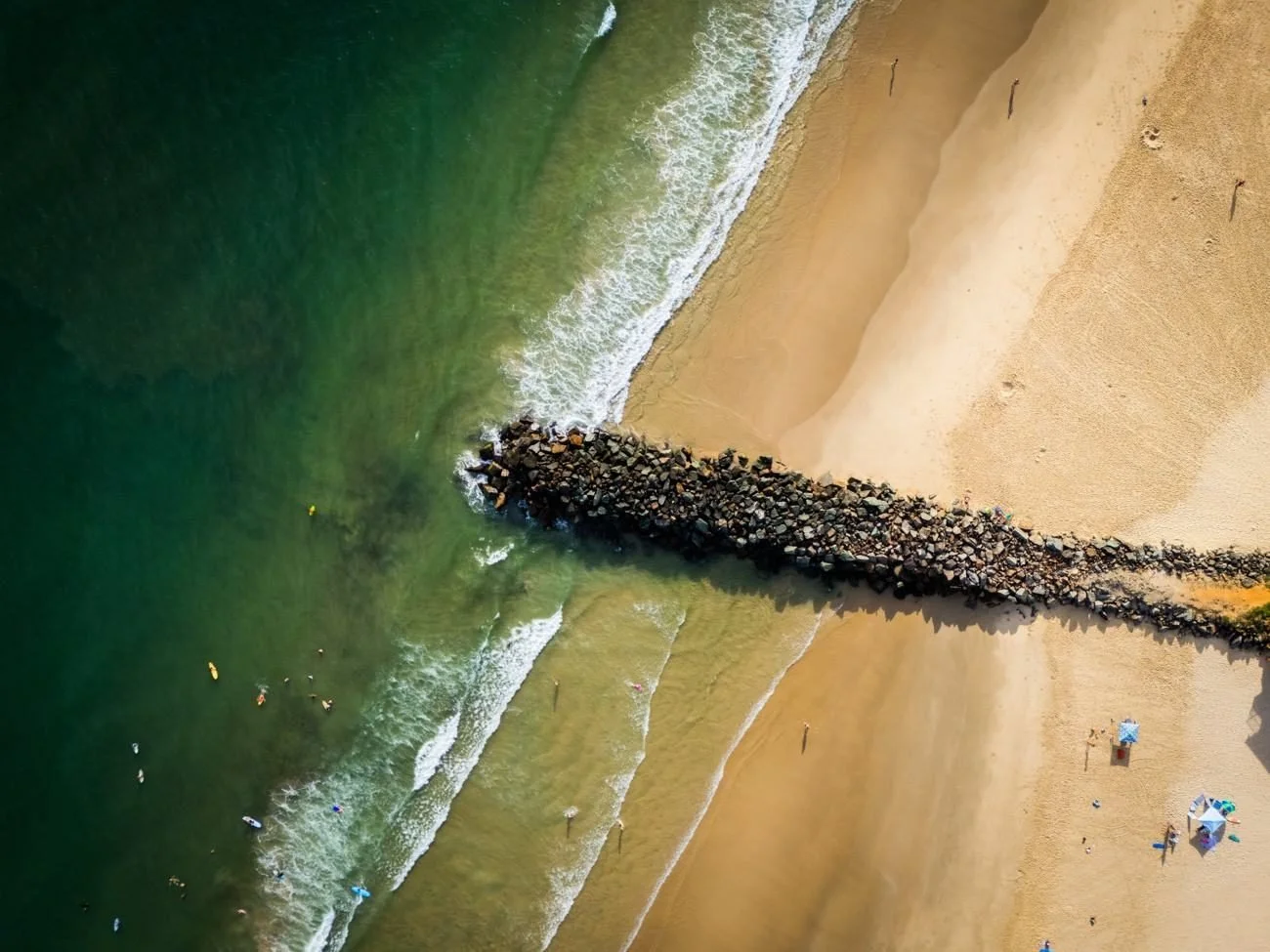 Overhead drone photo of a surf beach and rock wall