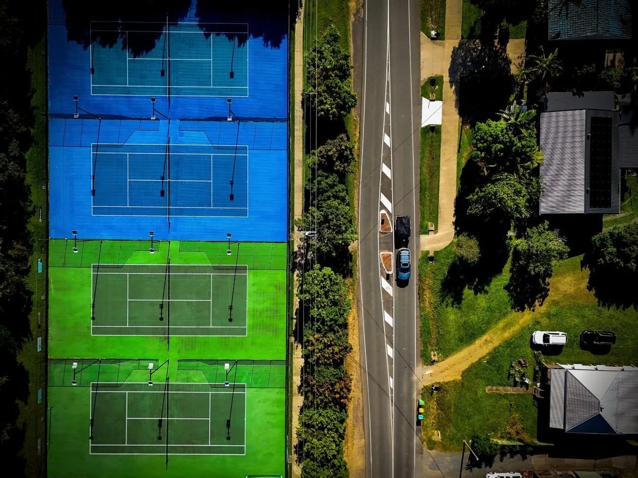 Top-down drone photo of club tennis courts beside a road