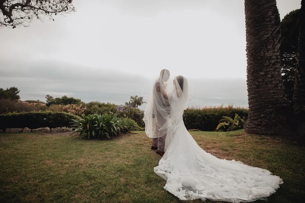 Bride and groom under the veil on the lawn at La Venta Inn beside a palm